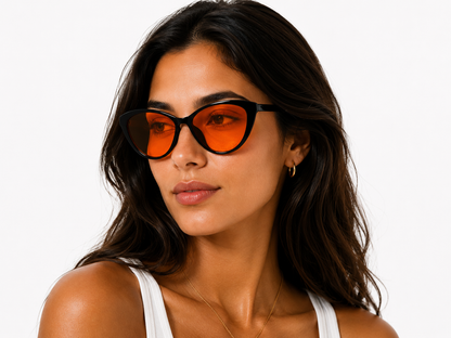 Model wearing Deep Drift cat eye blue light blocking sleep glasses with orange lenses and black frame for evening screen use and night time routines
